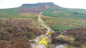 A photo of step 32 of the Burbage Rocks & Higger Tor Walk route, with yellow arrows superimposed to show the way.