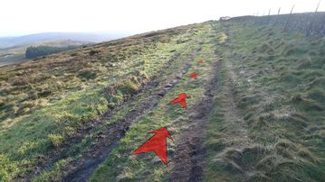 A photo of step 5 of the Cats Tor Walk route, with red arrows superimposed to show the way.
