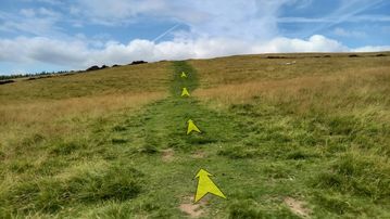 A photo of step 14 of the Kinder Reservoir Walk route, with yellow arrows superimposed to show the way.
