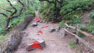 A photo of step 14 of the Lud's Church Walk route, with red arrows superimposed to show the way.